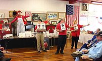 An auctioneer and her assistants scan the crow...